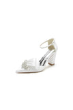 White Satin Heels Featuring a Large Decorative Bow and Metallic Heel